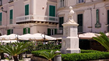 TROPEA, İtalya - Haziran 02, 2025 Tropea, Calabria, Güney İtalya 'da restoranları ve palmiye ağaçları olan bir meydanda beyaz mermer heykel