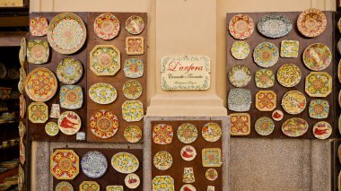 TROPEA, İtalya - Haziran 02, 2025 - Tropea, İtalya 'daki bir hediyelik eşya dükkanının önünde geleneksel Calabrian seramik tabakları ve çömlek sergisi