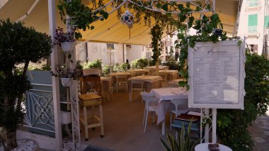 TROPEA, İtalya - Haziran 02, 2025 - Bitkilerle dekore edilmiş bir gölgelik altında düzenlenmiş açık masa ve sandalyeler, Tropea 'da akşam yemeği için davetkar bir atmosfer yaratıyor