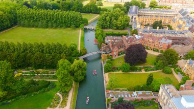 Cambridge Üniversitesi, İngiltere 'deki yeşil çimler ve tarihi binalardan geçen nehir kamerasındaki uçan teknelerin hava görüntüsü.