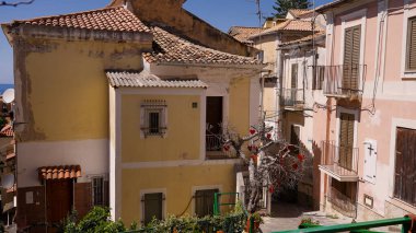 PIZZO, ITALY - 3 Haziran 2025 - Pizzo, Calabria, İtalya 'da yaşlanan cepheleri ve dekore edilmiş ağaçları gösteren geleneksel evler