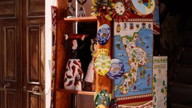 PIZZO, ITALY - 3 Haziran 2025 - Calabrian kültürü ve gelenekleri sergilenen renkli seramik hediyelik eşyalar, heykelcikler, dekoratif plakalar ve Pizzo 'daki bir dükkanda sergilenen bölge haritası