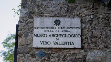 CALABRIA, İtalya - 3 Haziran 2025 - Eski bir taş duvara iliştirilmiş Vibo Valentia arkeoloji müzesini gösteren mermer tabelanın yakın görüntüsü