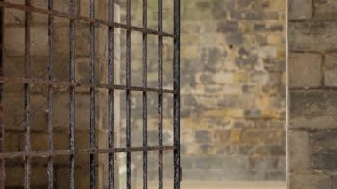 Paslı metal kapı hafifçe açık, eski bir taş duvarı ortaya çıkarıyor, gizem ve tarih duygusu yaratıyor.