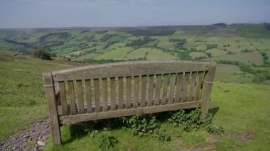 Tahta bank ziyaretçileri dinlenmeye ve Kuzey York Moors Ulusal Parkı 'ndaki yeşil vadinin nefes kesici manzarasına hayran olmaya davet ediyor.