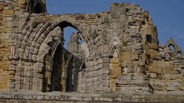 Whitby Abbey harabelerinin mimari ayrıntıları. Kemerli ve karmaşık taş işçiliği mavi gökyüzü altında. Whitby, North York Moors Ulusal Parkı, İngiltere 'de.