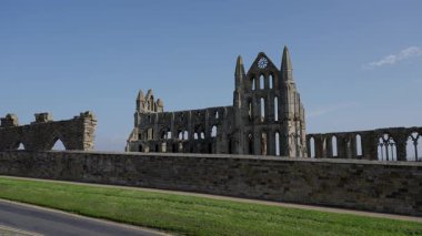 Whitby Abbey 'nin enkazının manzarası İngiltere' deki Kuzey York Moors Ulusal Parkı 'ndaki açık mavi gökyüzüne karşı görkemli bir şekilde duruyor.