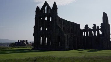 Whitby Abbey, Birleşik Krallık 'taki Kuzey York Moors Ulusal Parkı' nda yeşil bir çayıra gölge düşürüyor.