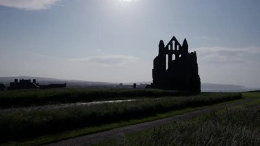 Whitby Abbey 'nin dramatik silueti Kuzey York Moors Ulusal Parkı' nda günbatımında harabeye döndü.