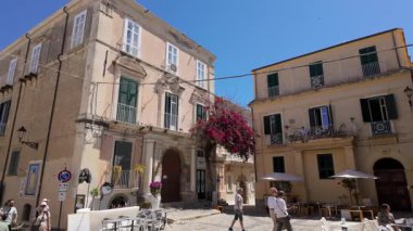 TROPEA, İTALYA - 2 Haziran 2025 - Tropea, Calabria 'da bir meydanda yürüyen turistler, güneşli bir yaz gününde tarihi binalar ve begonvil çiçekleri ile