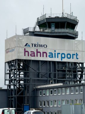 HAHN, GERMANY - 1 Haziran 2025 - Frankfurt Hahn Havalimanı kontrol kulesi Bulutlu bir günde büyük bir Triwo reklamı