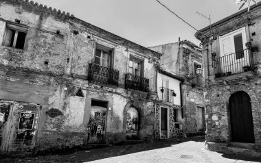 CALABRIA, İTALYA - 4 Haziran 2025 - Eski, yıkılan binalar Zungri, İtalya 'da dar, güneşli bir cadde üzerinde, zamanın geçişini ve çürümenin güzelliğini gözler önüne seriyor