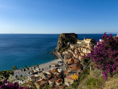 Güneşli bir yaz gününde, Ruffo Kalesi ve plajı olan renkli Scilla köyünün panoramik manzarası.