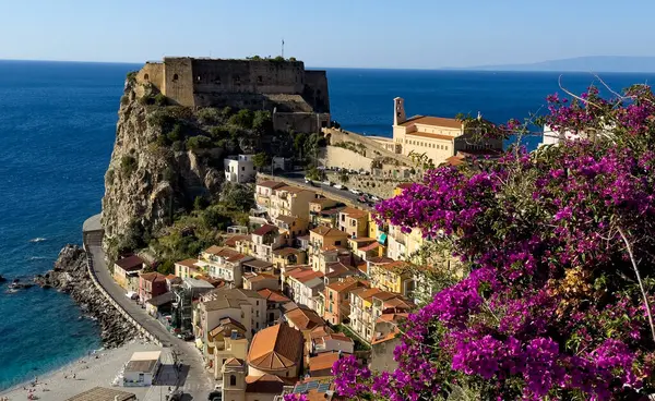 Güney İtalya, Calabria 'da Ruffo Kalesi' nin uçurumunda renkli Scilla evlerini çerçeveleyen mor bougainvillea çiçekleri.