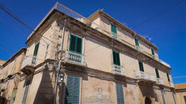 Tropea, İtalya 'da geleneksel mimari, mavi gökyüzüne karşı yeşil panjurları, beyaz balkonları ve elektrik hatları olan eski bir konut binası
