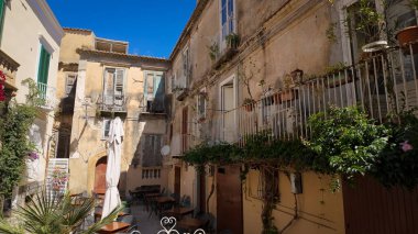 Yıpranmış binaların balkonlarının altında sıralanmış masa ve sandalyeler Tropea, İtalya 'da tuhaf bir yemek ortamı yaratıyor.