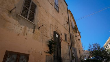 Geleneksel İtalyan mimarisi, İtalya 'nın Tropea kentindeki yıpranmış bir binada, canlı mavi bir gökyüzünün altında sergilenmektedir.