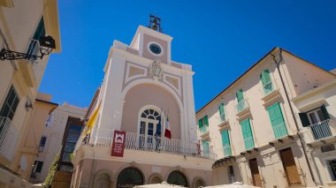 TROPEA, İtalya - 2 Haziran 2025 - Güneşli bir günde rüzgarda sallanan İtalyan ve Avrupa bayraklarıyla Tropea belediye binasının alçak açılı görüntüsü