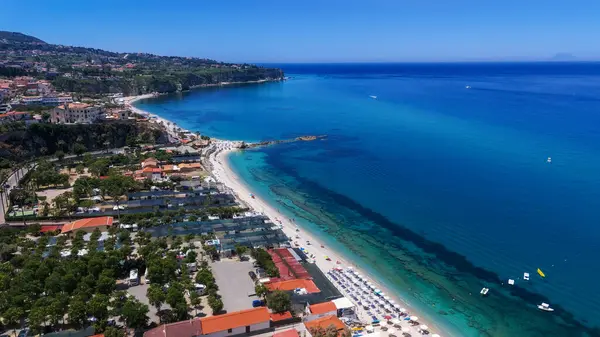 Tropea, Calabria 'nın hava manzarası güneşli bir yaz gününde güzel kıyı şeridini ve kristal berrak turkuaz suyu gösteriyor.