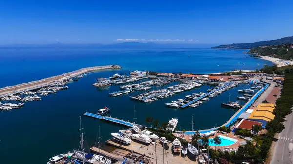 Güney İtalya, Calabria 'da güzel bir yaz gününün tadını çıkaran pek çok beyaz tekneyle Tropea limanının havadan görüntüsü.