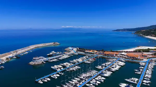 Güney İtalya, Calabria 'da güneşli yaz gününün tadını çıkaran demirli teknelerle dolu Tropea limanının hava manzarası.