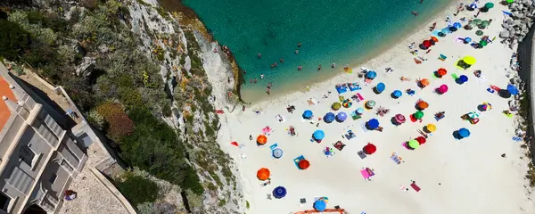 Tropea, Calabria, Güney İtalya 'da yaz tatilinin tadını çıkaran turistler, renkli şemsiyelerle cennet gibi beyaz kumsallarda geziyorlar.