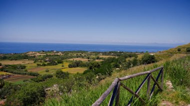 Tyrhenian Denizi manzarası ve Zungri, Calabria yakınlarındaki bir tepeden ekilmiş tarlalar ön planda ahşap bir çitle