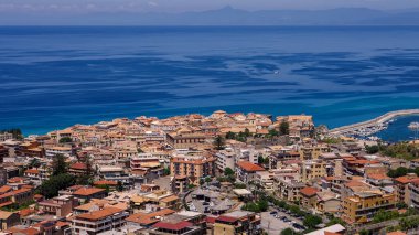Tropea 'nın havadan görünüşü, renkli binaları ve kristal berrak suları ile Tırmık Denizi' ne bakan bir uçuruma tünemiş büyüleyici bir kasaba.