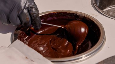 Pizzo, Calabria, İtalya 'da ünlü Tartufo tatlısını hazırlamak için bir pasta şefi tarafından kaşıkla karıştırılan erimiş siyah çikolataya yakın çekim