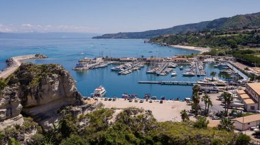 Güney İtalya 'nın Calabria kentindeki Tyrhenian Denizi' ne bakan rıhtımlı tekneleri ve kayalıkları olan Tropea limanının havadan görünüşü güneşli bir yaz gününde