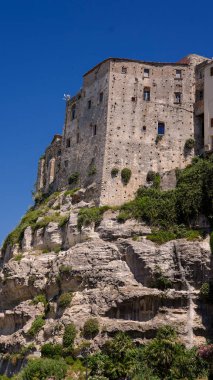 Güney İtalya 'da güneşli bir yaz gününde Calabria' da popüler bir turizm merkezi olan Tropea 'ya bakan bir uçurumun üzerinde duran eski bina.