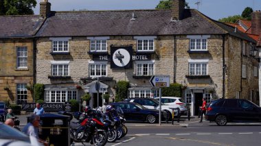 HELMSLEY, İngiltere - 12 Haziran 2025 - Stone park etmiş arabaları ve motorsikletleri olan bir otel inşa etti, Helmsley, Kuzey York Moors Ulusal Parkı 'nda güneşlenerek güneşlendi