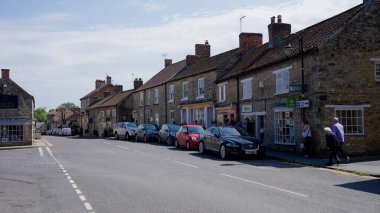 HELMSLEY, İngiltere - 12 Haziran 2025 - Güzel güneşli bir günde Kuzey York Moors Ulusal Parkı 'nda bulunan Helmsley adlı pitoresk bir kasabada gezen ve alışveriş yapan turistler