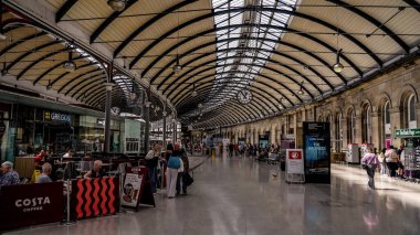 NEWCASTLE, İngiltere - 13 Haziran 2025 Newcastle Merkez İstasyonu 'na hareket eden gezginler ve gezginler zarif cam ve demir mimarisi tarafından korunuyorlar.