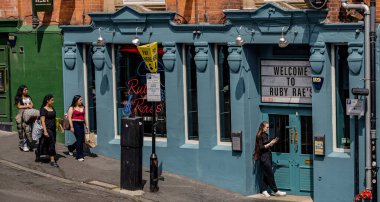 NEWCASTLE, İngiltere - 13 Haziran 2025 - Güneşli bir yaz gününde, Newcastle caddelerinde Ruby Rae 'nin barının yakınında yürüyen kadınlar