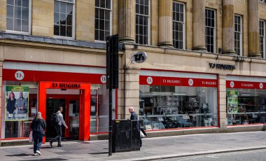 NEWCASTLE, İngiltere - 13 Haziran 2025 Newcastle, İngiltere 'de güneşli bir günde TJ Hughes mağazasının önünden geçen yayalar