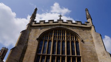 Cambridge, İngiltere 'deki sivri kemerli cam pencerenin üzerinde Latince yazıyla Büyük Kilise cephesinin alçak açılı görüntüsü.