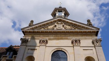 Cambridge, İngiltere 'de mavi gökyüzüne bakan dekoratif kubbeli ve armalı Senato Binası ön cephesi.