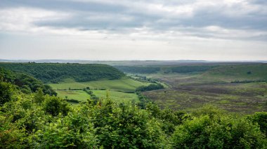 Kuzey York Moors Ulusal Parkı 'nda bulutlu gökyüzü altında uzanan yemyeşil vadi ve tepeler