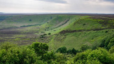 Kuzey York Moors Ulusal Parkı 'nda bulutlu gökyüzü altında uzanan yemyeşil vadi ve tepeler