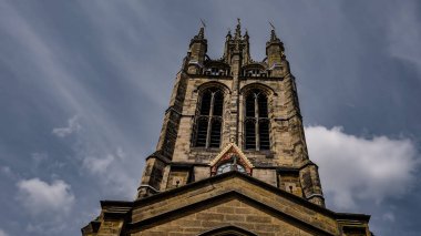 St. Nicholas Katedrali 'nin arka planında bulutlu bir gökyüzü olan saat ve kulesinin alçak açılı görüntüsü Tyne üzerinde Newcastle' da.