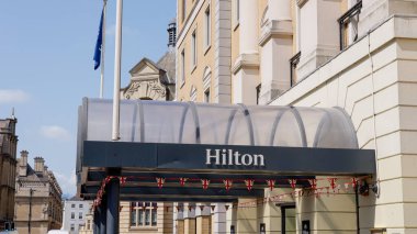 CAMBRIDGE, İngiltere - 11 Haziran 2025 - Cambridge, İngiltere 'de küçük İngiliz bayraklarıyla süslenmiş Hilton otelinin girişindeki modern tepe örtüsü
