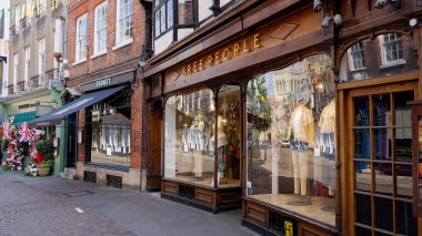 CAMBRIDGE, İngiltere - 11 Haziran 2025 - Cambridge, İngiltere 'deki son moda eğilimlerini gösteren mankenlerle Özgür İnsanlar giyim mağazasının ahşap vitrini