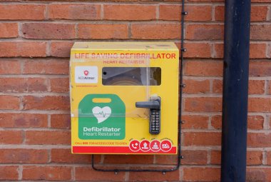 LEEDS, İngiltere - 12 Haziran 2025 - Sarı defibrilatör kutusu duvara asılı, Leeds, İngiltere 'de acil tıbbi yardım öneriyor