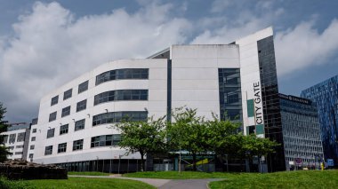 NEWCASTLE, UK - 13 Haziran 2025 - İngiltere 'deki Newcastle City Gate' in modern mimarisi, yeşil ağaçlar ve bulutlu bir gökyüzüne karşı dimdik ayakta duruyor