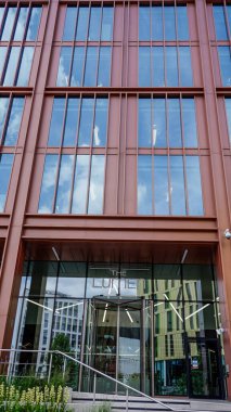 NEWCASTLE, İngiltere - 13 Haziran 2025 - Newcastle şehir merkezinde gökyüzünü yansıtan döner giriş ve cam cepheli modern ofis binası