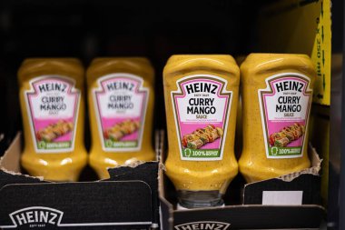 Heinz Curry Mango sosu şişeleri market rafında parlıyor ve çeşitli tavuk ve domuz eti yemekleri için ideal olan eşsiz lezzet karışımlarını sergiliyorlar. - FRANKFURT, Almanya - 21 Mart 2025