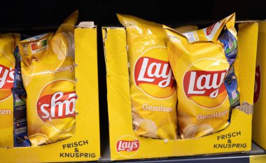 Lay 'in tuzlu patates cipsleri göz alıcı bir vitrin kutusunda sunuluyor ve raflarda markaların özel ürünlerini sergiliyor. - FRANKFURT, Almanya - 21 Mart 2025