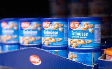 Mavi ambalajlı kavrulmuş tuzlu fıstıklardan oluşan görsel olarak cazip bir düzenleme aperatif cazibesini ve tadını ön plana çıkarıyor. - FRANKFURT, Almanya - 21 Mart 2025