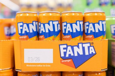 Bir perakende mağazasında canlı renkler ve marka kimliğiyle düzgünce istiflenmiş Fanta portakallı soda kutularının çekici bir gösterisi. - FRANKFURT, Almanya - 21 Mart 2025